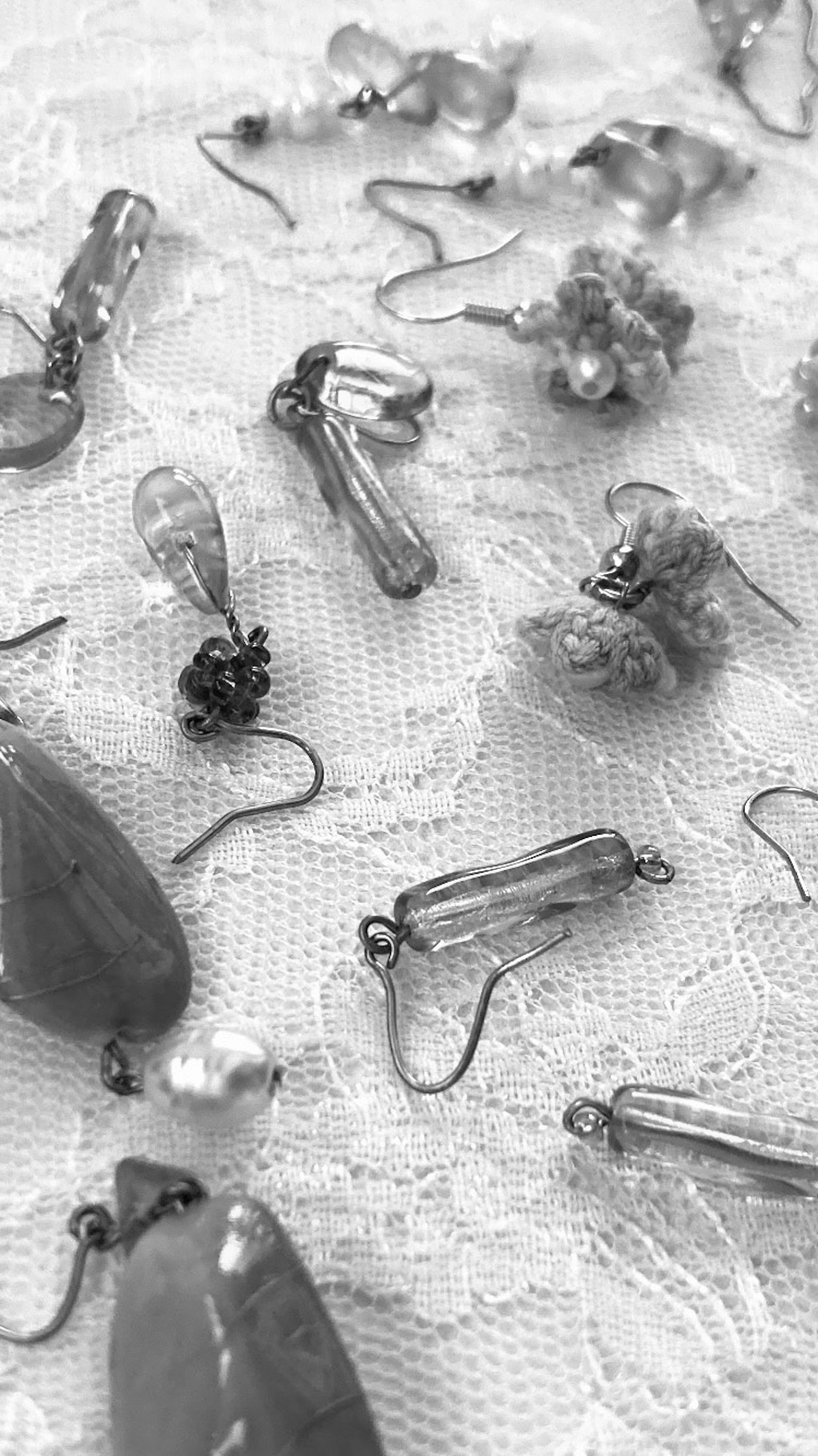 Vari pendenti in cristallo e perline trasparenti sparsi su un tessuto di pizzo