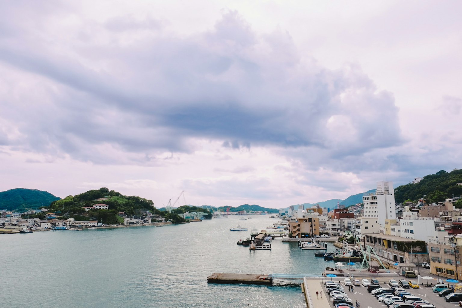ทิวทัศน์ของเมืองชายฝั่งที่มีท่าเรือ เมฆเบาในท้องฟ้า เรือและอาคารใกล้เคียง