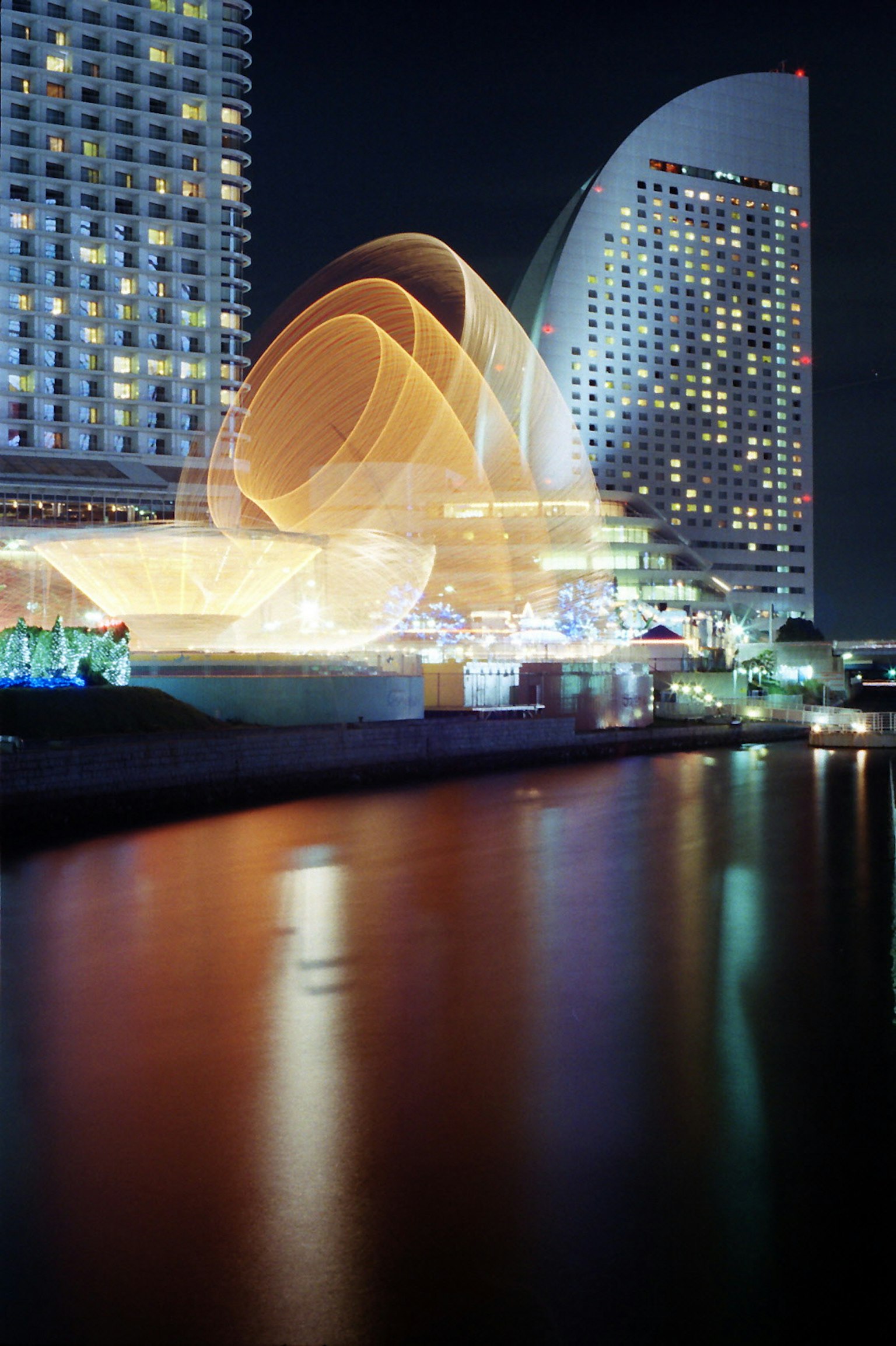 Edificios modernos de Yokohama iluminados por la noche con reflejos en el agua