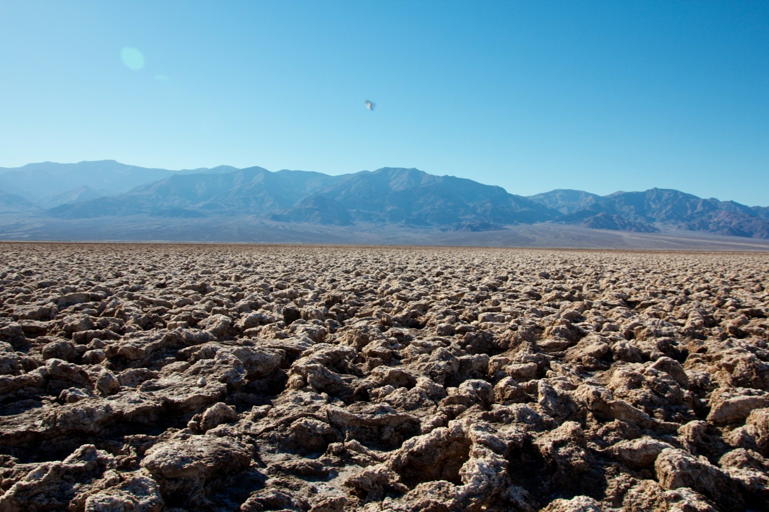 Un paesaggio di terra secca e crepata con montagne in lontananza