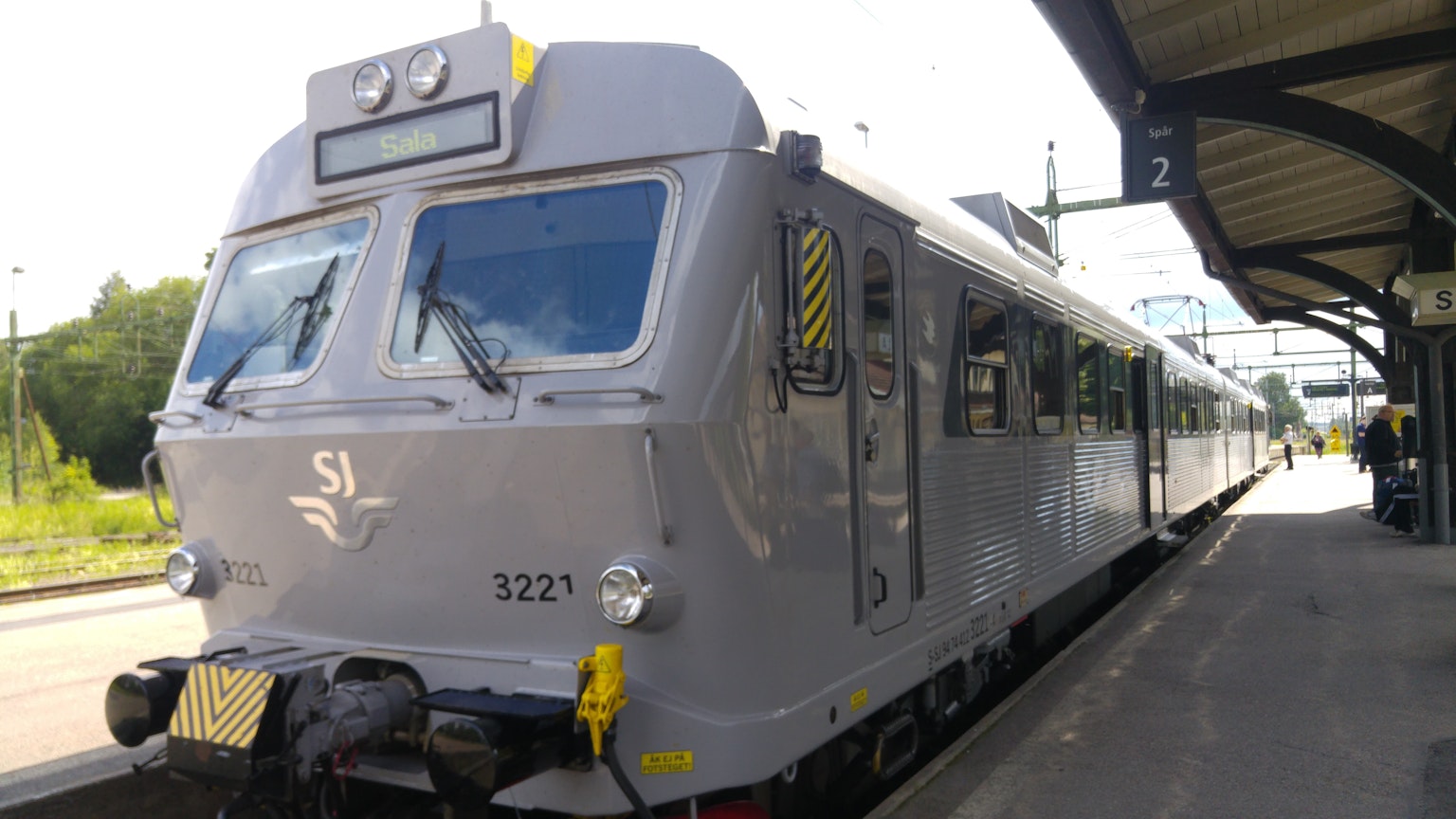 Silver train parked at the station with surrounding landscape