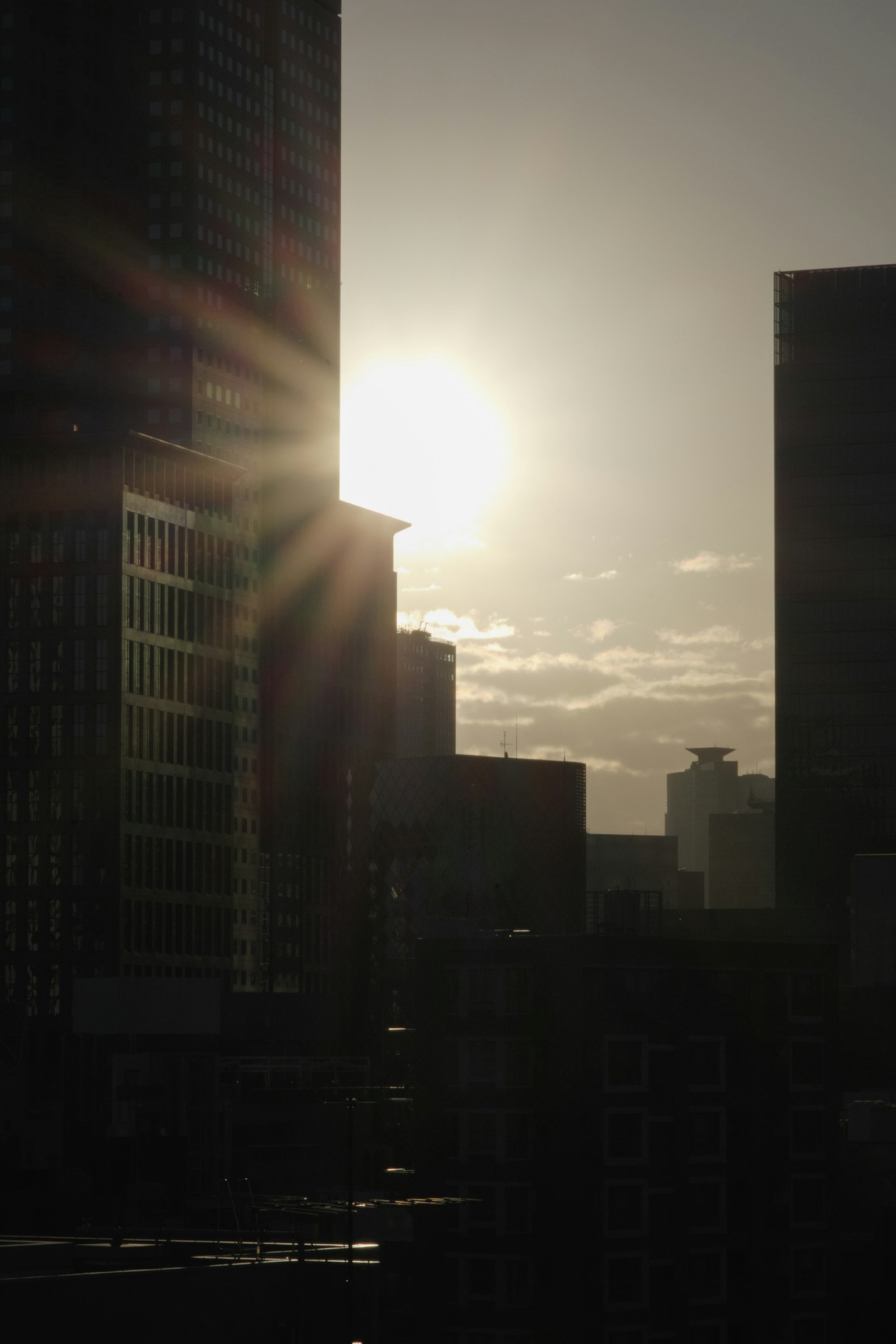 Silhouette von Wolkenkratzern gegen eine untergehende Sonne mit Lichtstrahlen