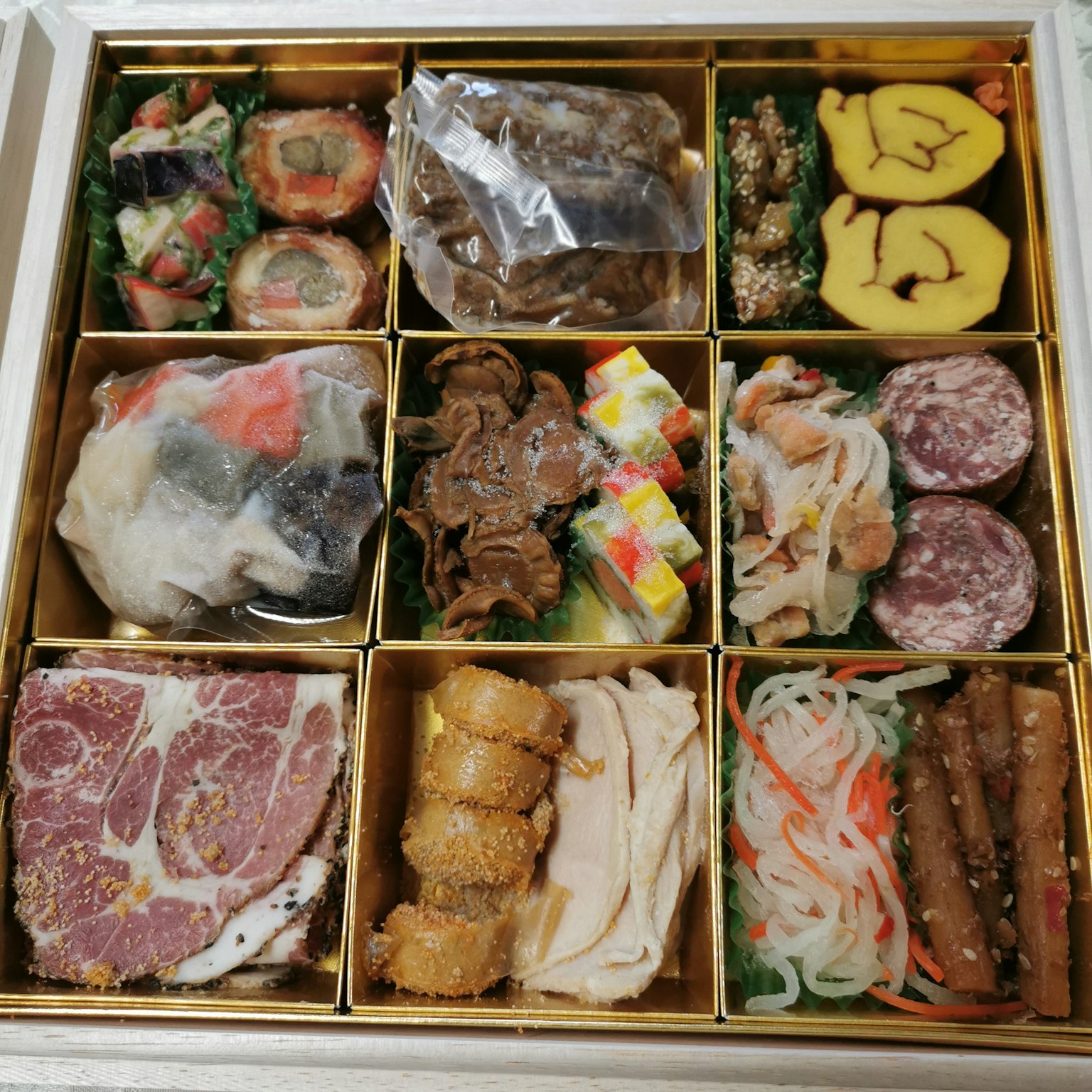Un assortiment coloré de plats disposés dans une boîte à bento dorée