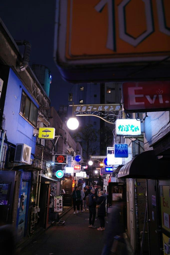 ruelle commerçante de nuit avec enseignes lumineuses et passants