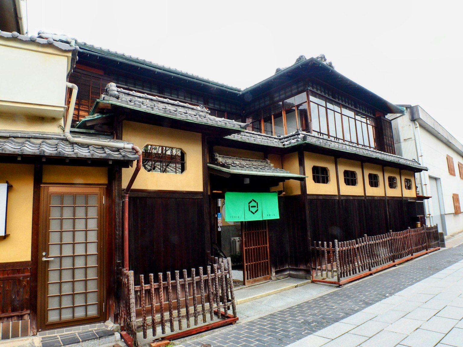 传统日本建筑外观，木质结构和绿色暖帘