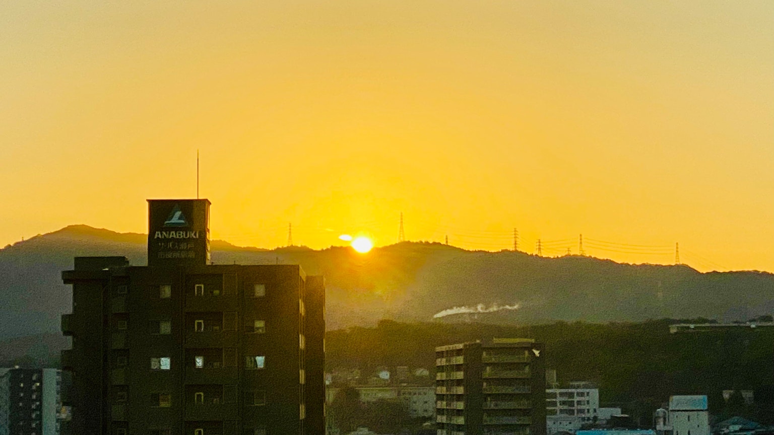 Sunset over mountains with silhouettes of buildings in the foreground