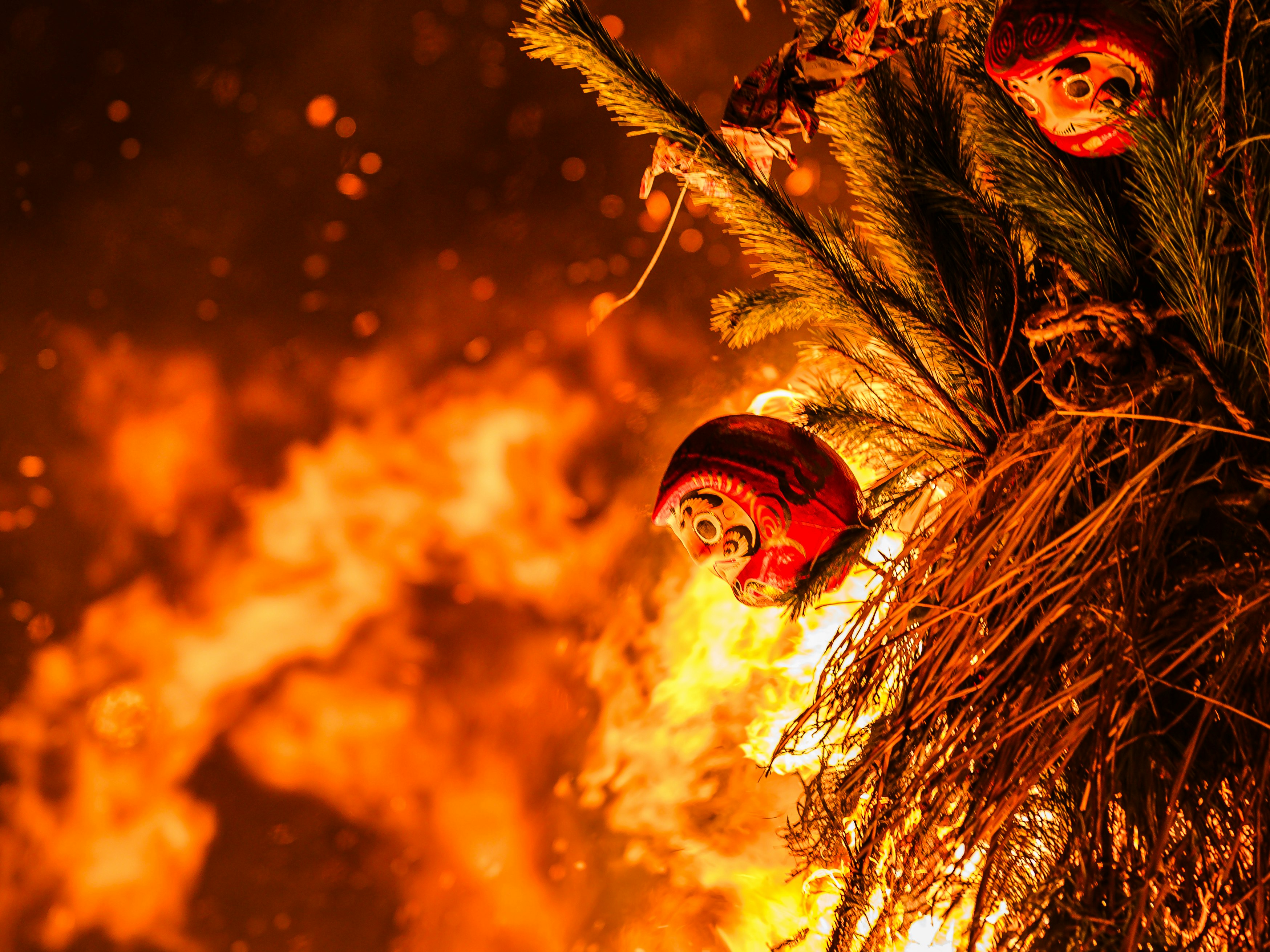 Halloweenartige Nachtszene mit Masken und Flammen