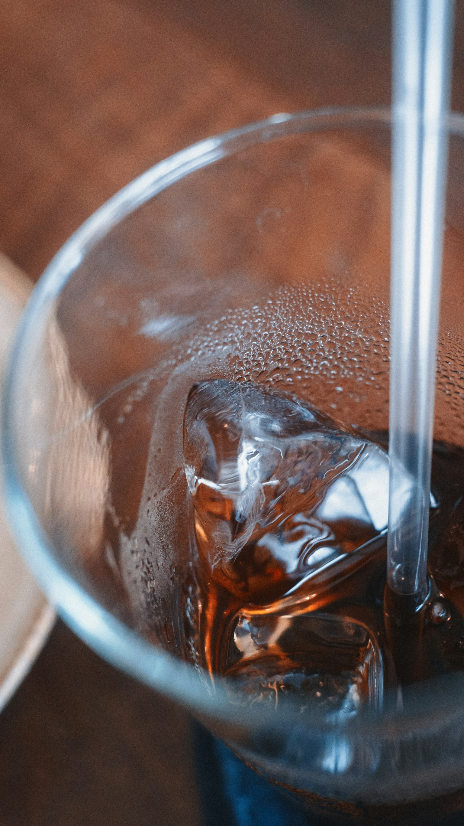 氷が入った飲み物のグラスのクローズアップ 透明なストローが見える