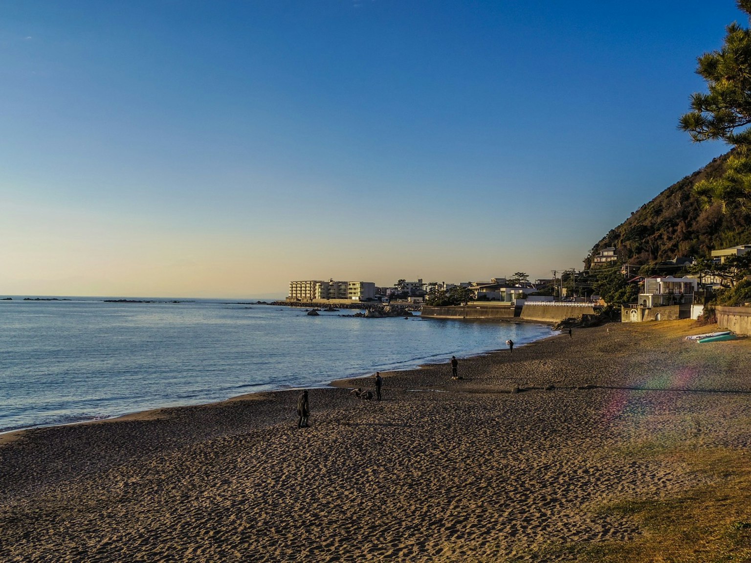 Calm sea and sandy beach view with blue sky and mountain backdrop
