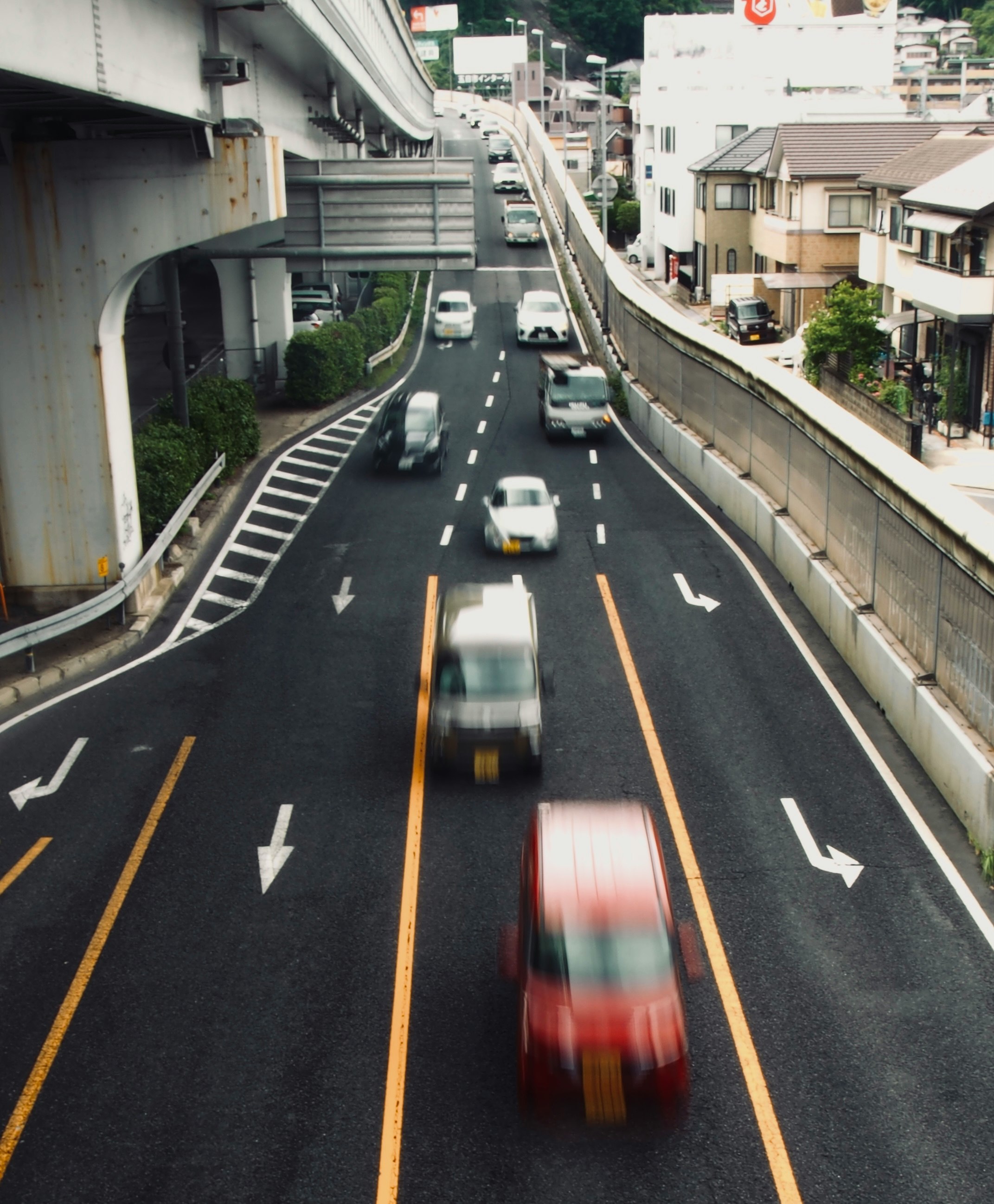 高架下の車道を走る車のある都市の通り