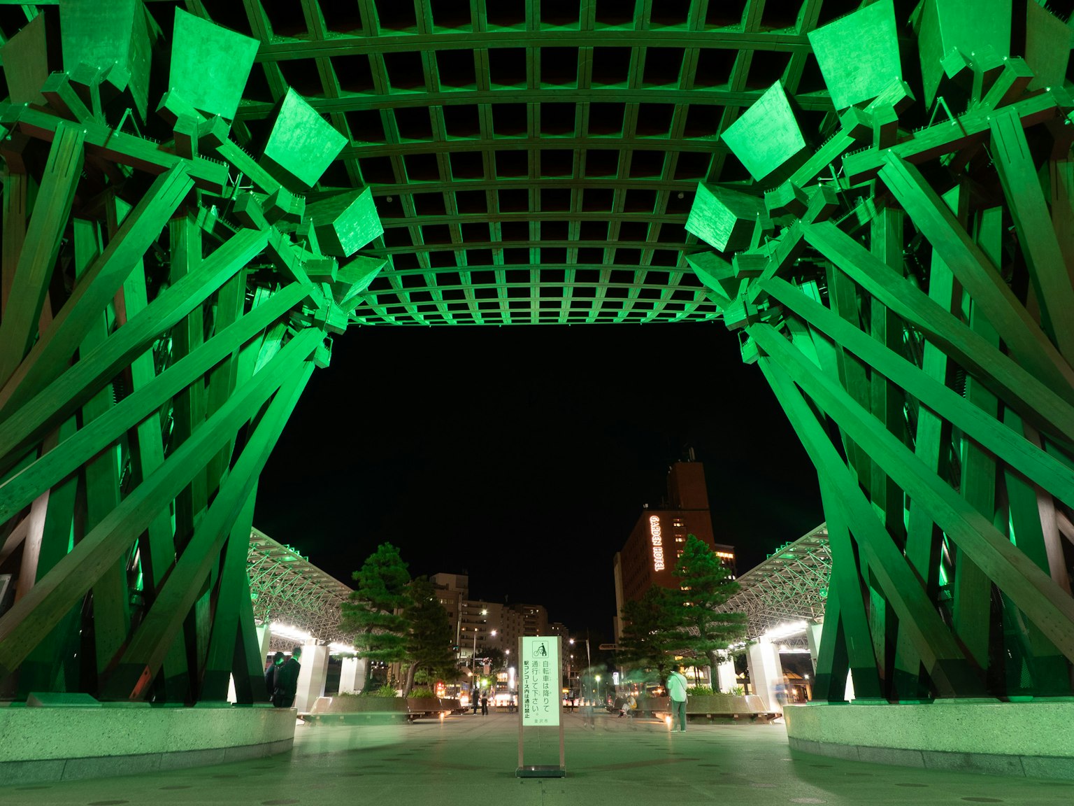 Arco architettonico unico illuminato di verde di notte con paesaggio urbano circostante