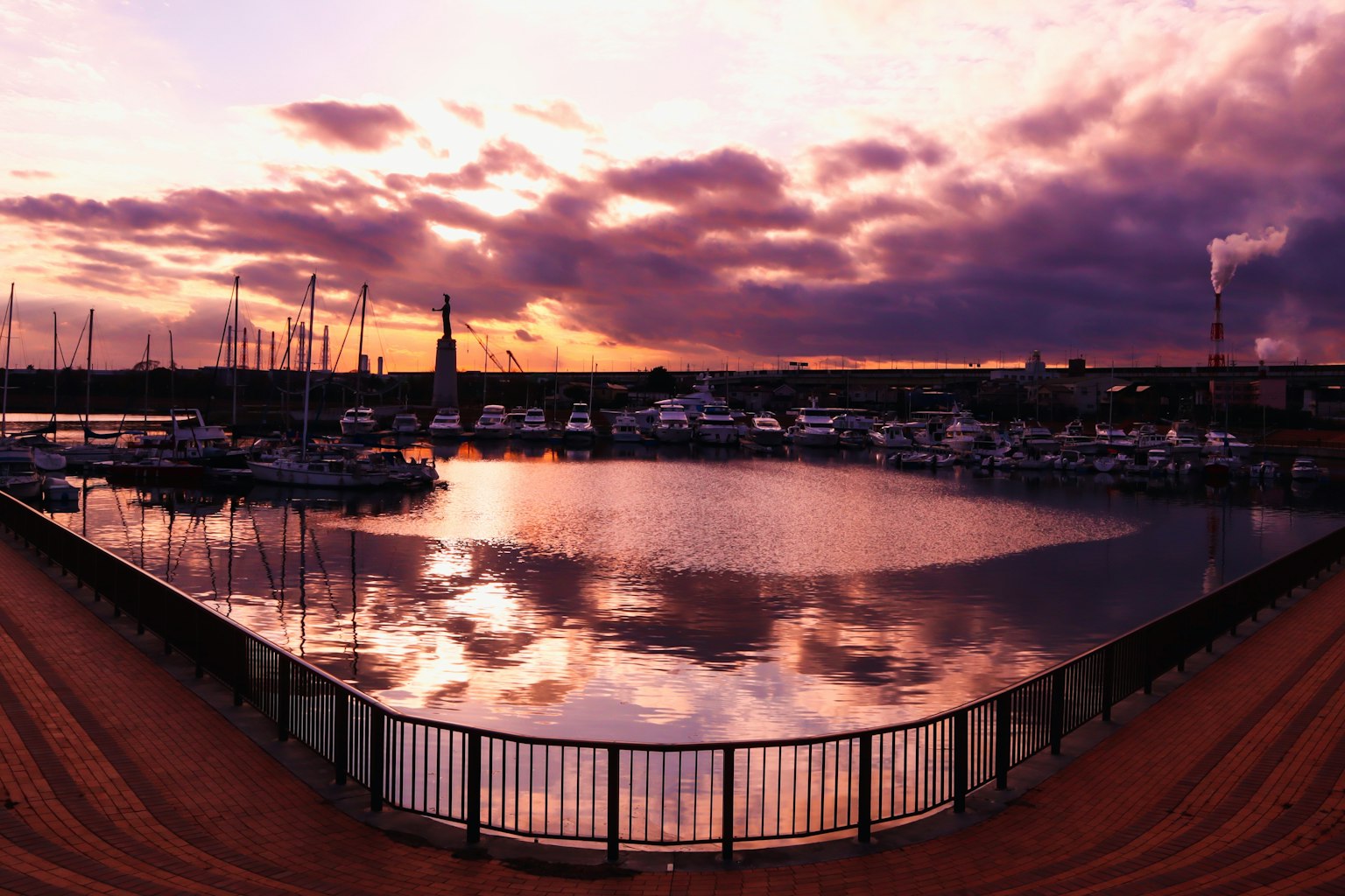 Vue du port au coucher du soleil avec des bateaux et des nuages réfléchissants