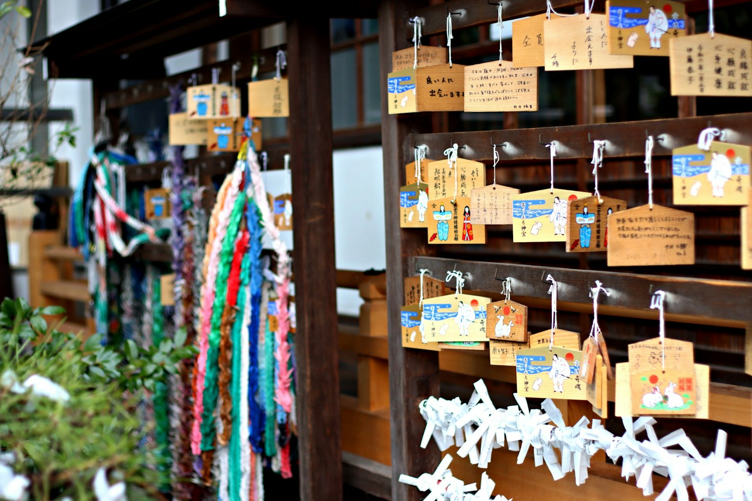 Pared de madera adornada con placas ema y talismanes en un santuario