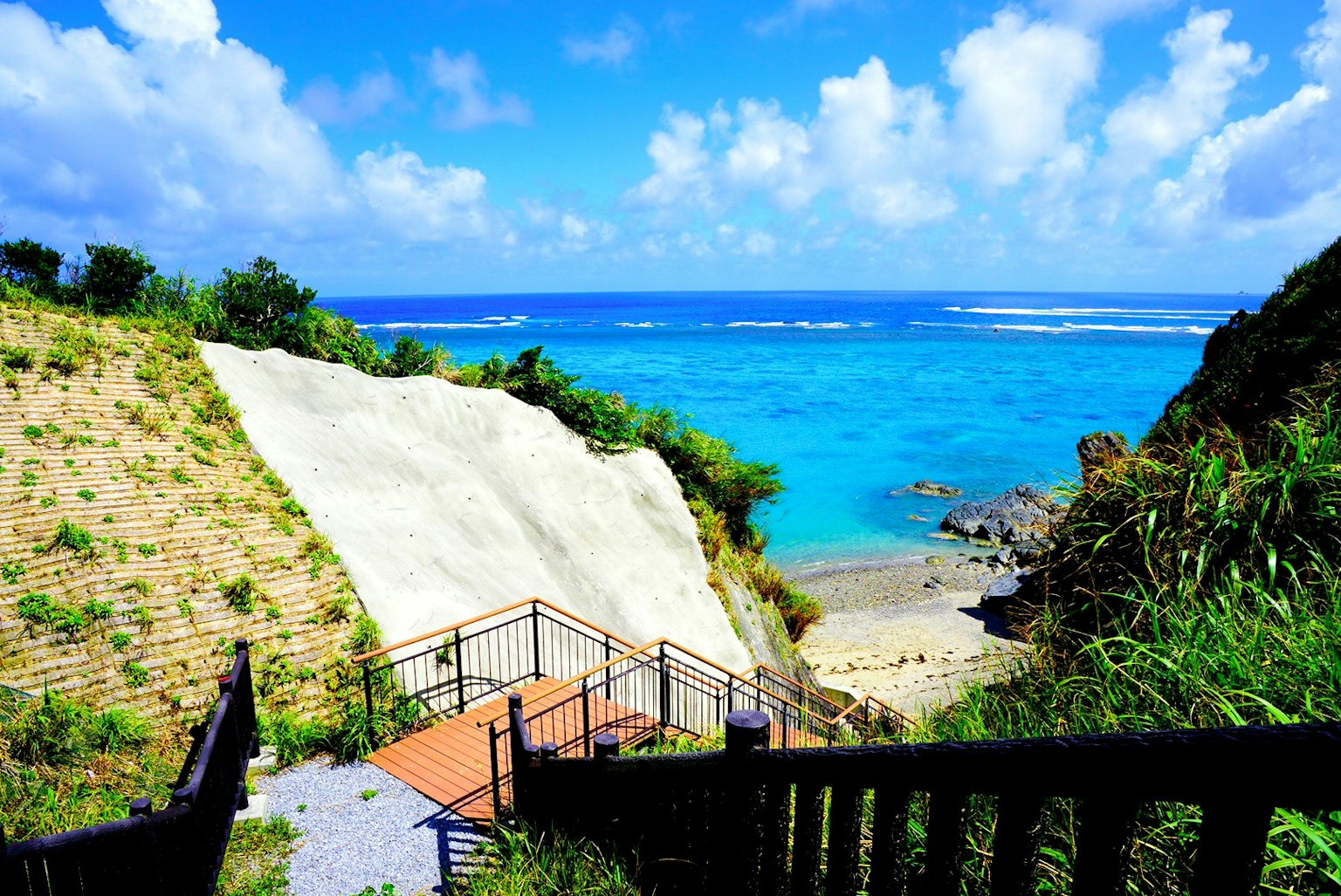 Scala che porta a una spiaggia con oceano blu e scogliere bianche