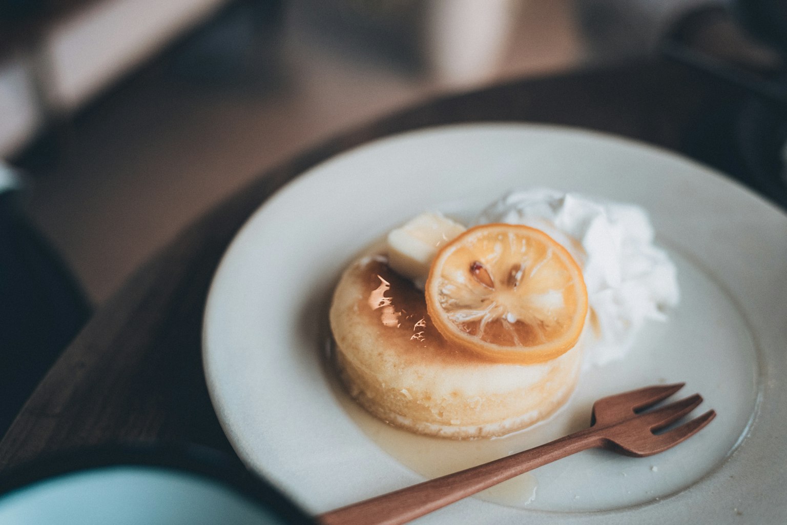 Panqueque cubierto con rodaja de limón y crema en un plato blanco