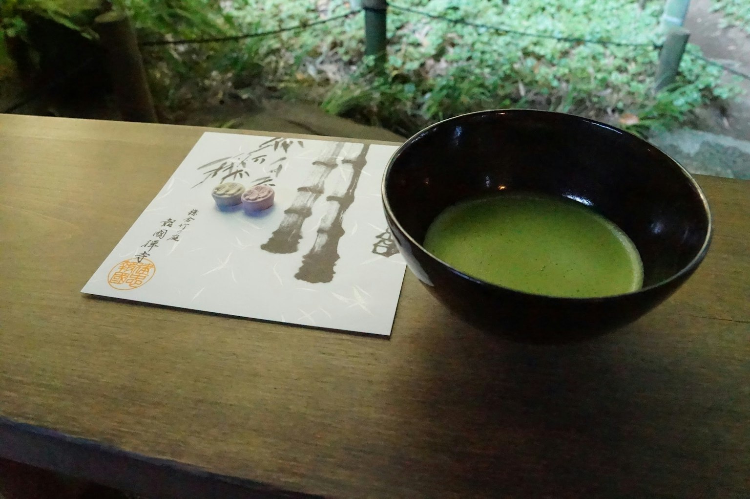 Un bol de thé matcha et un menu de sucreries japonaises sur une table en bois