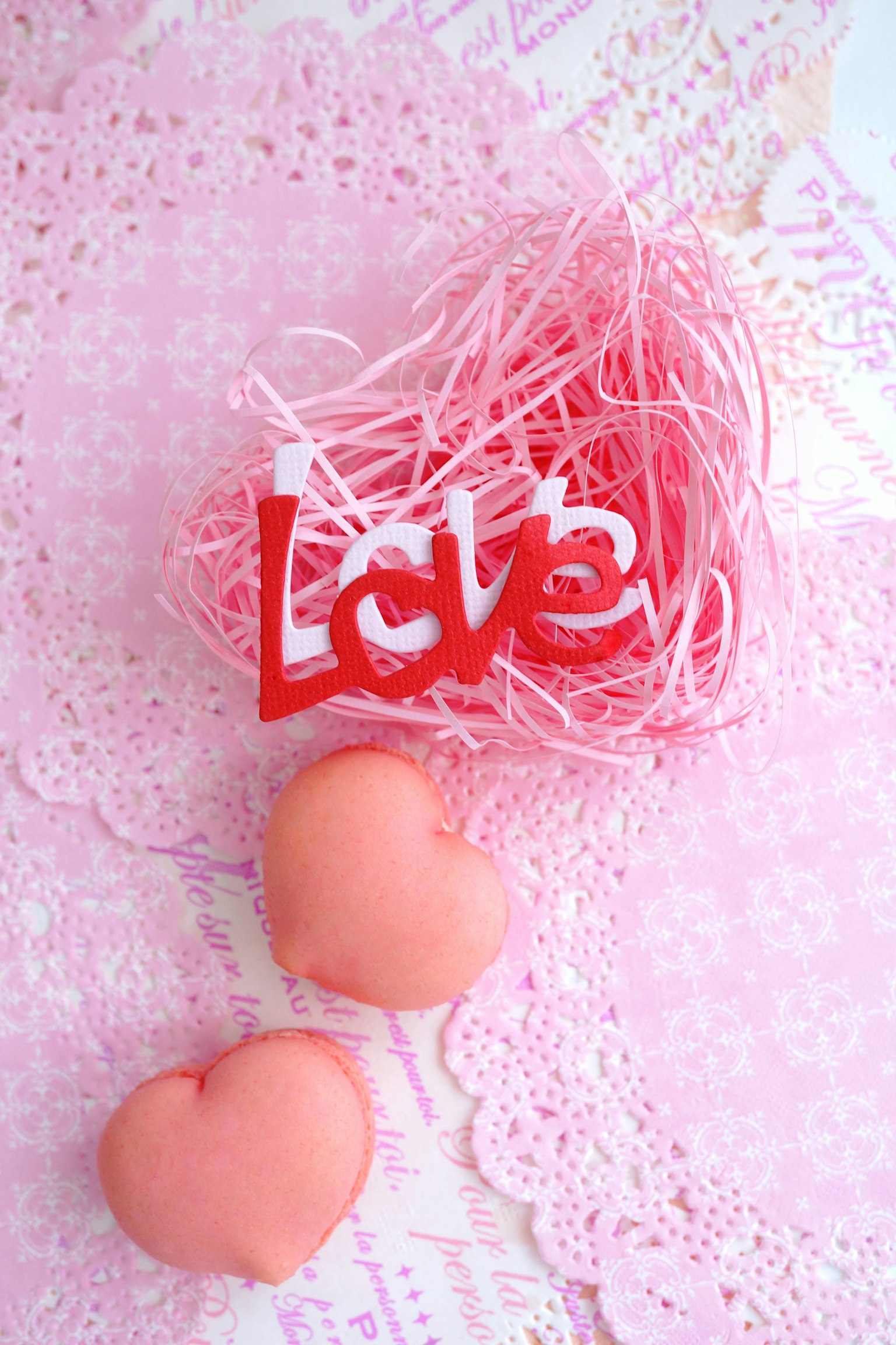 粉色背景上的红色心形'Love'文字与柔软的心形糖果和装饰性蕾丝
