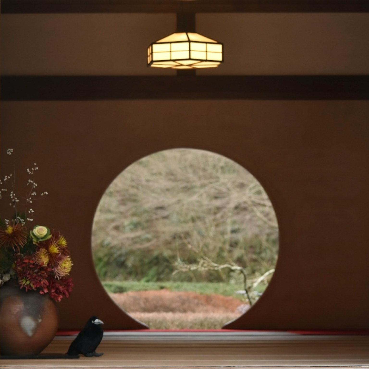 Vista attraverso una finestra rotonda che mostra la natura e un vaso di fiori