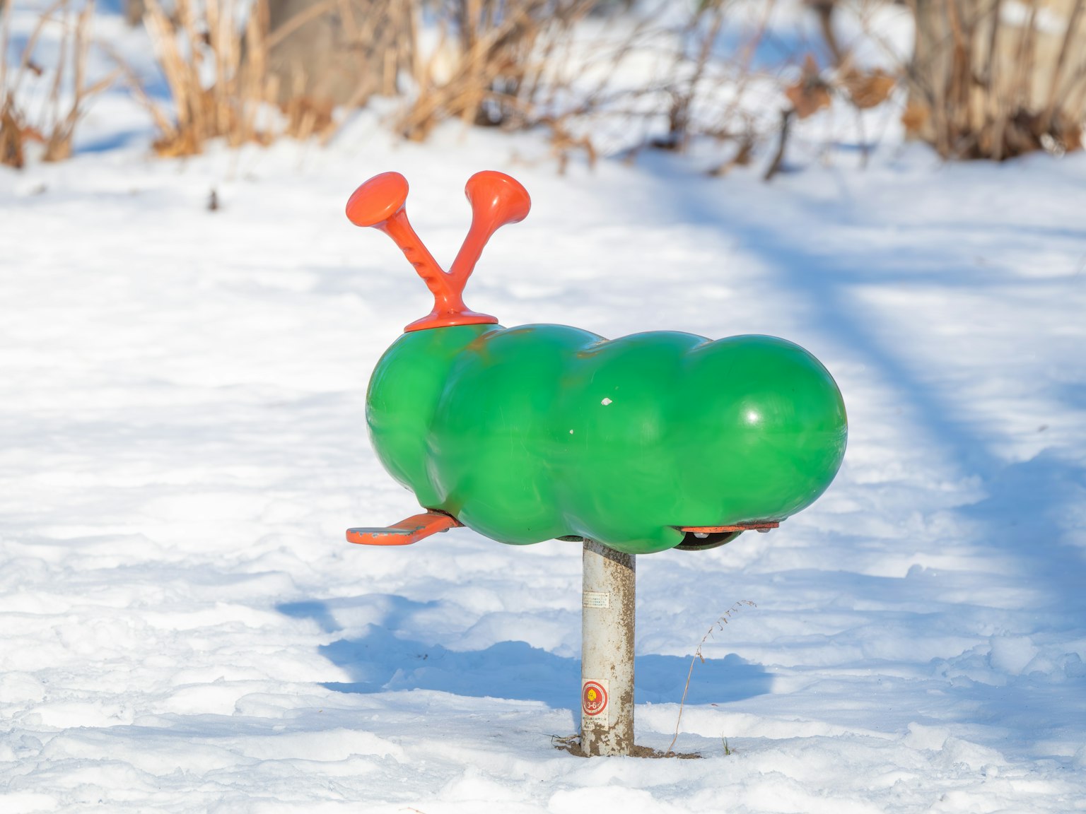 雪地上的绿色毛虫形状游乐设施带有红色触角