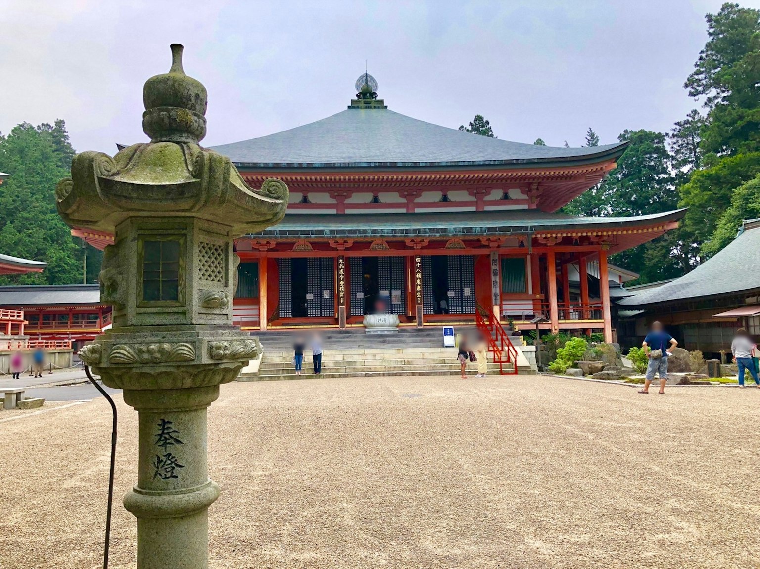 Stone lantern in front of a beautiful temple surrounded by lush greenery