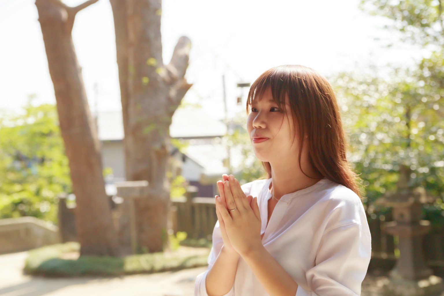 หญิงสาวที่กำลังอธิษฐานในสวน มีต้นไม้และแสงแดดเบลอเบาๆ
