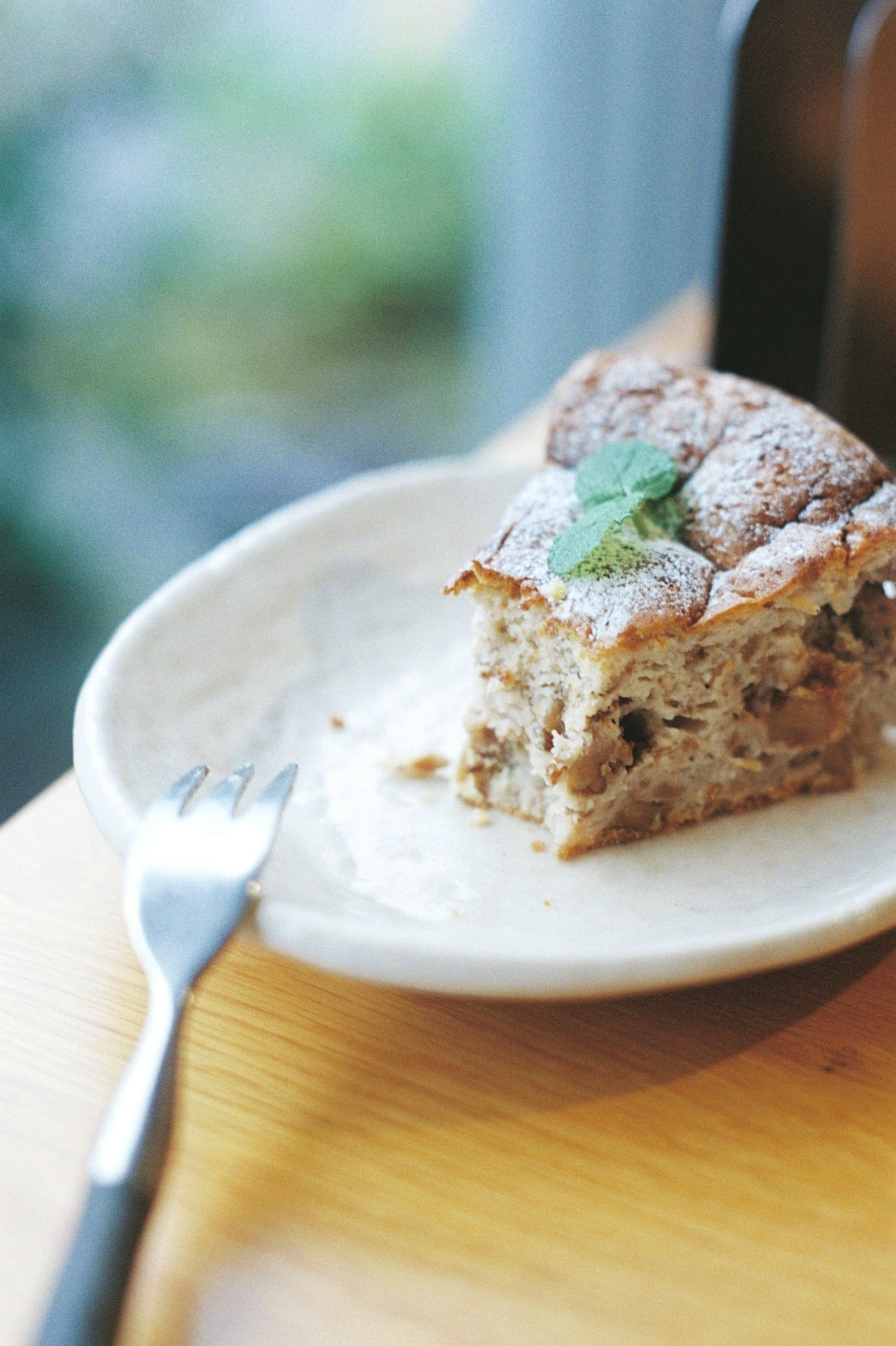A beautiful baked dessert on a white plate with a mint leaf garnish and a fork beside it