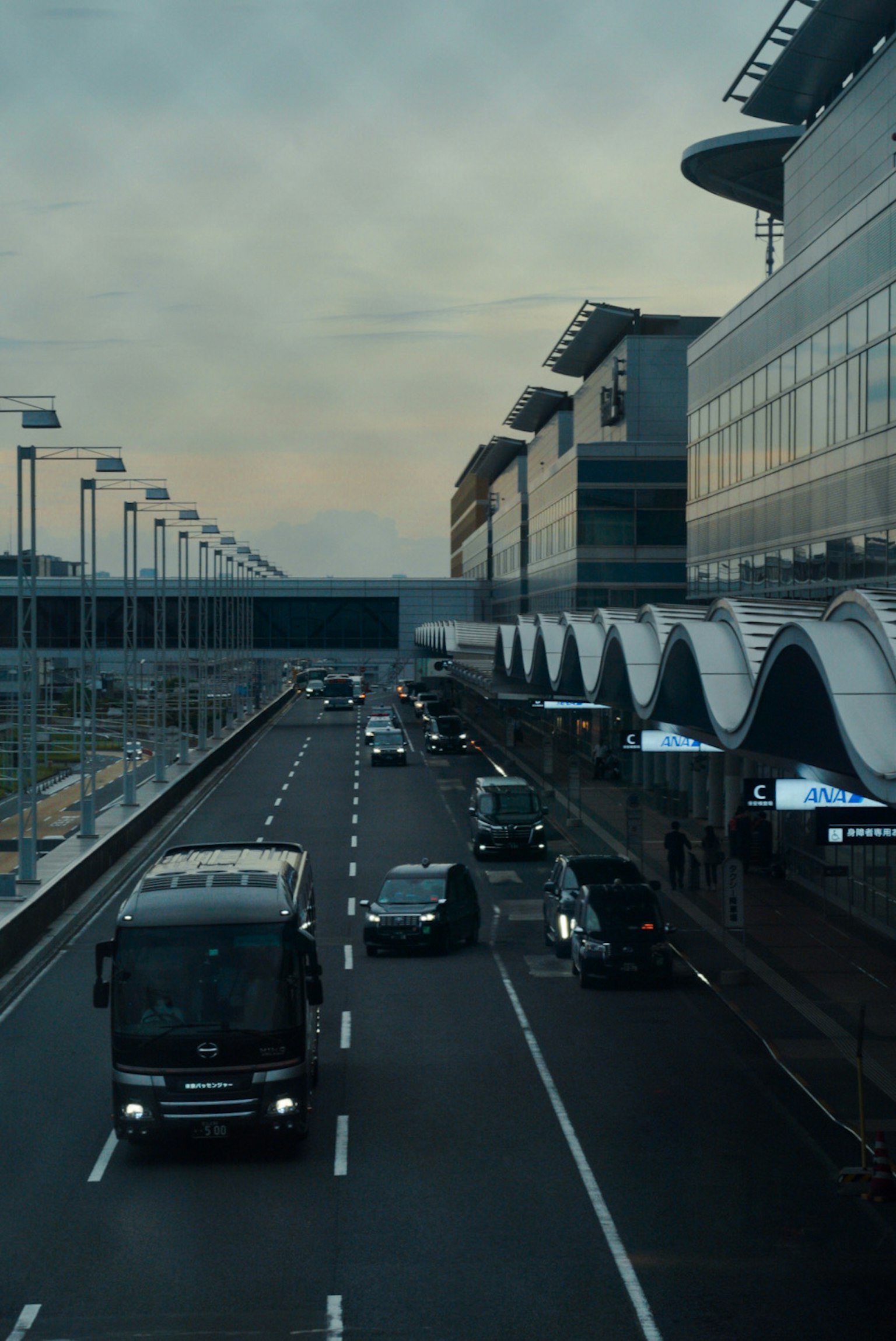 View of vehicles along the airport road with modern buildings