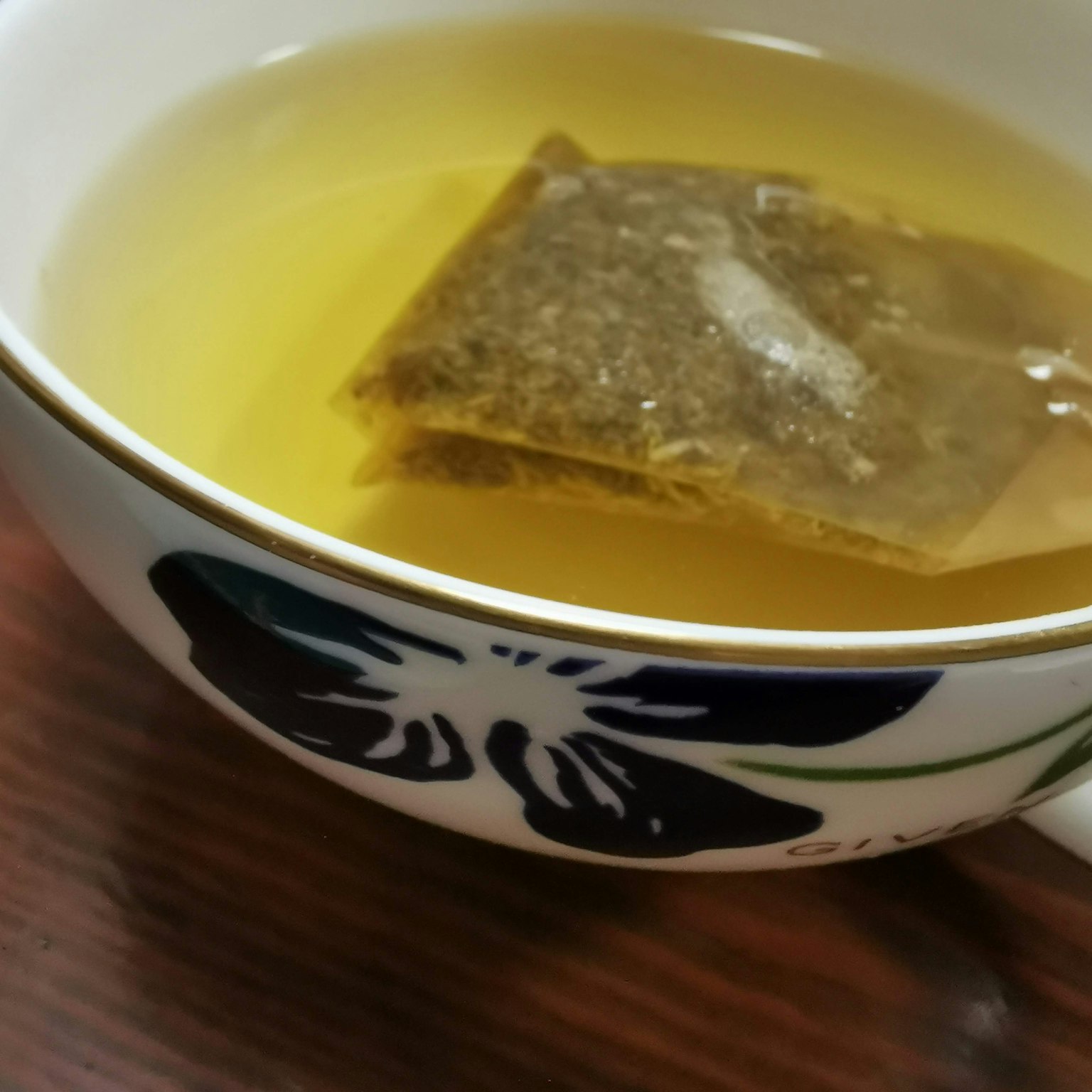 一杯淺綠色的茶中漂浮著一個茶包