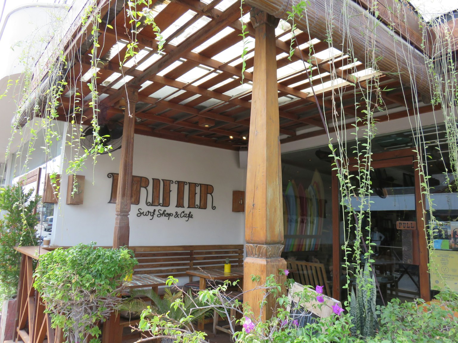 Vue extérieure d'un café avec structure en bois et plantes suspendues