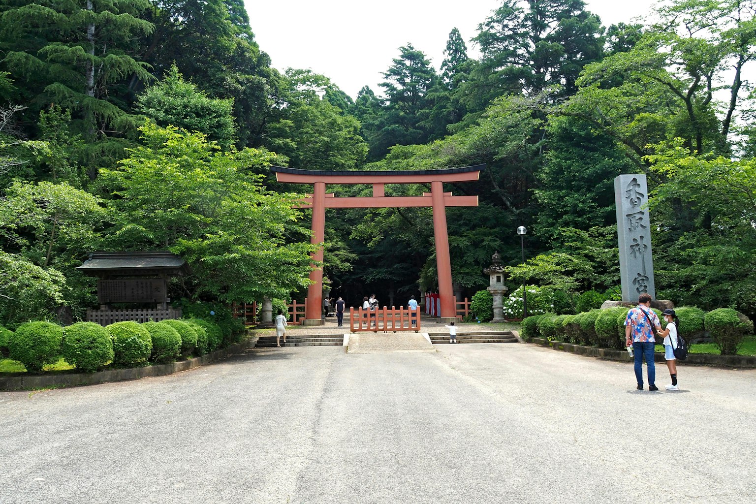Lối vào đền có cổng torii đỏ được bao quanh bởi cây cối và du khách
