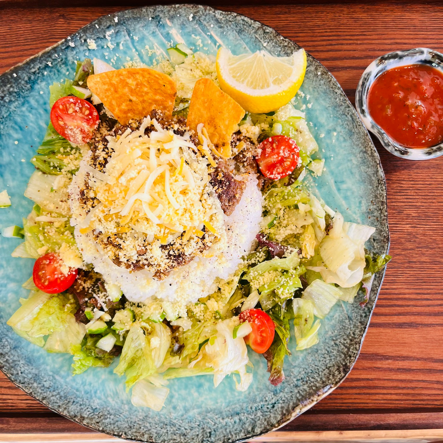 Ein lebhaftes Gericht mit Reis und Käse auf frischem Salat garniert mit Zitrone und Kirschtomaten