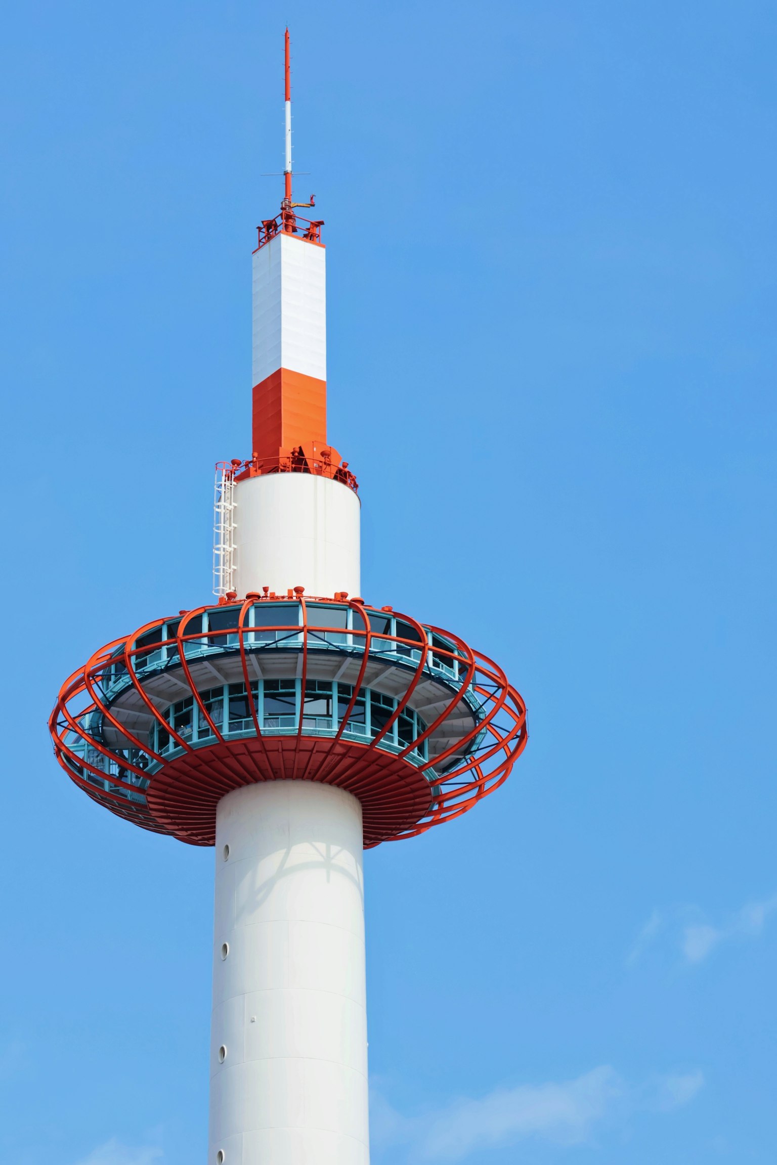 Bagian atas menara komunikasi merah dan putih di bawah langit biru