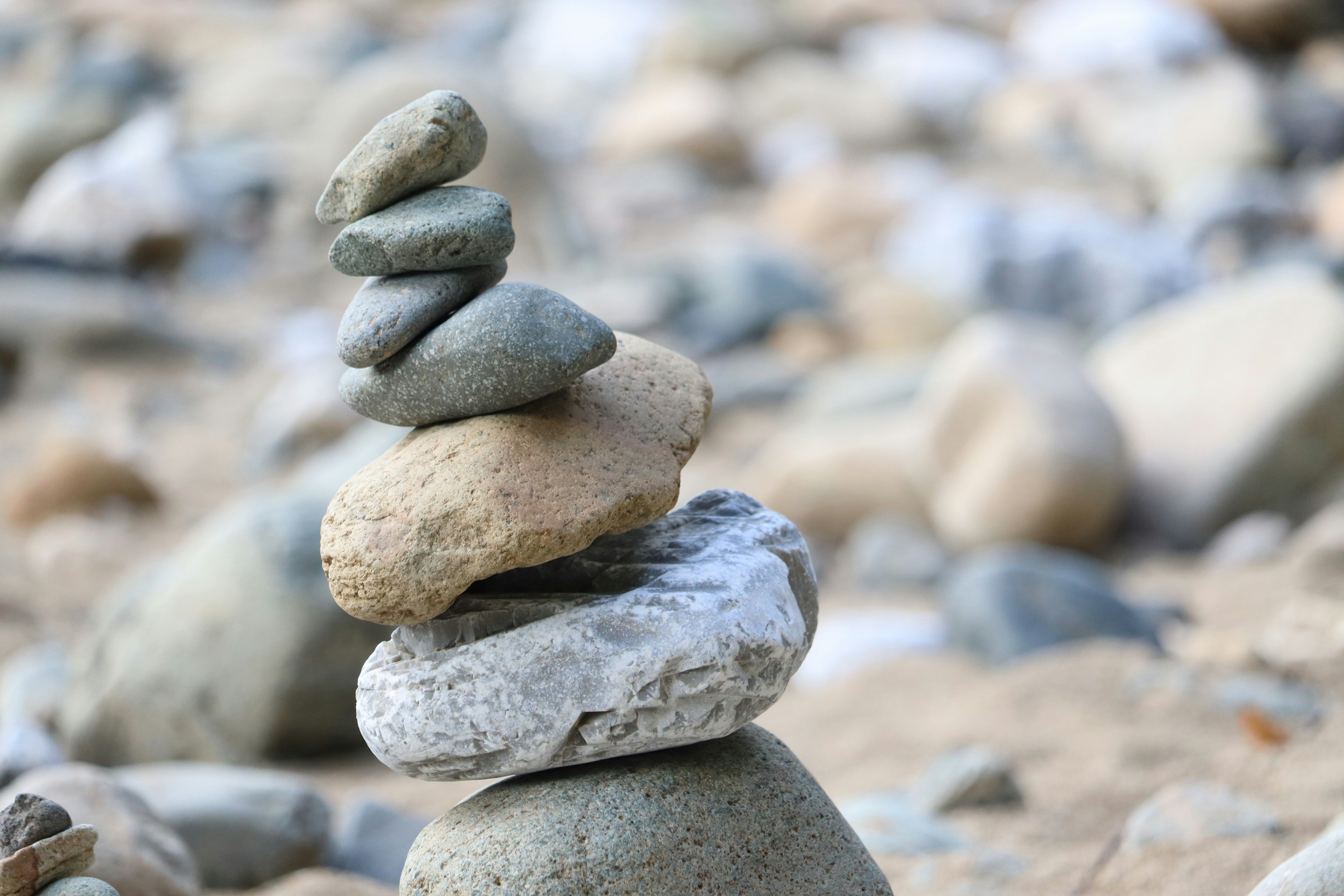 stacked balancing stones with a rocky riverbank background
