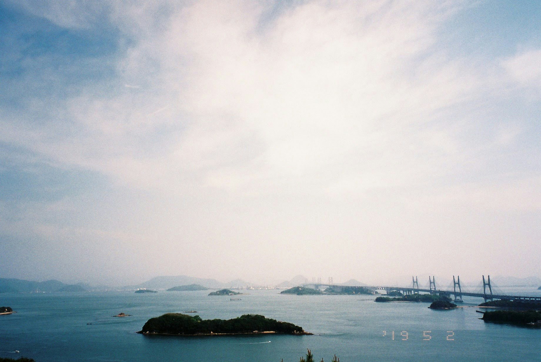 海上に浮かぶ小島と遠景の橋のある風景