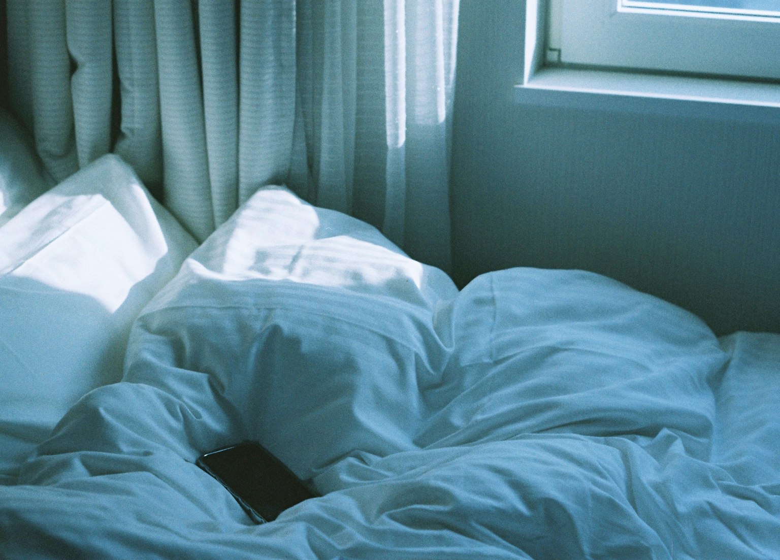 Angolo luminoso di una camera da letto con biancheria bianca morbida e tende