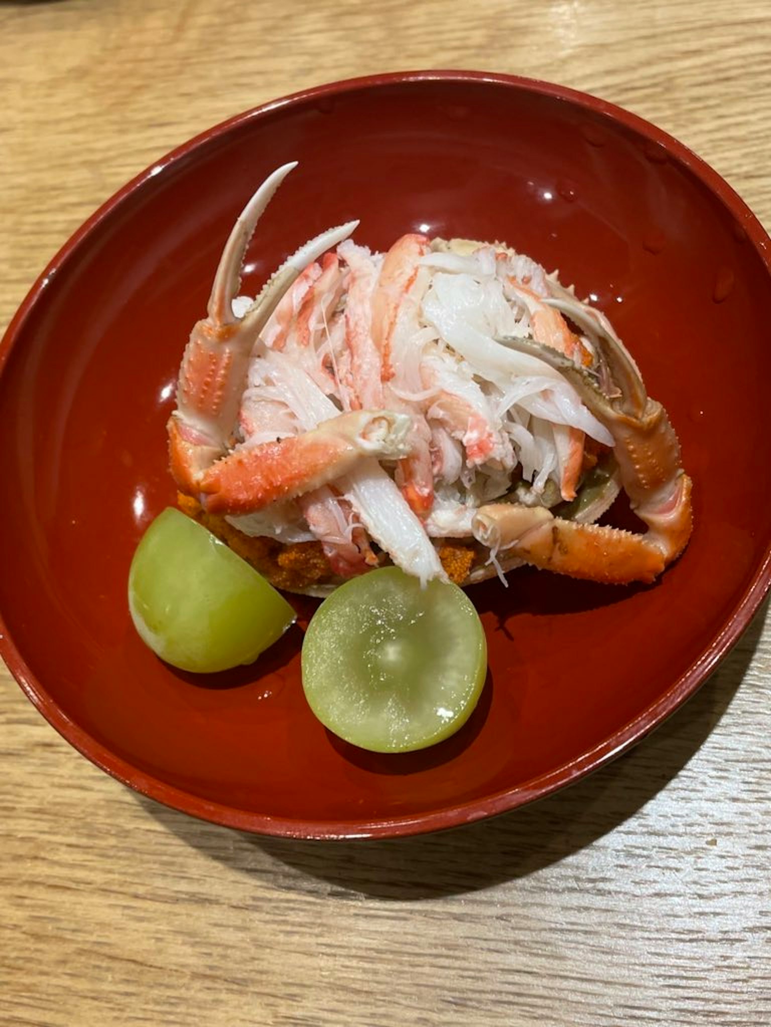 Piatto di granchio servito in una ciotola rossa con due fette di lime