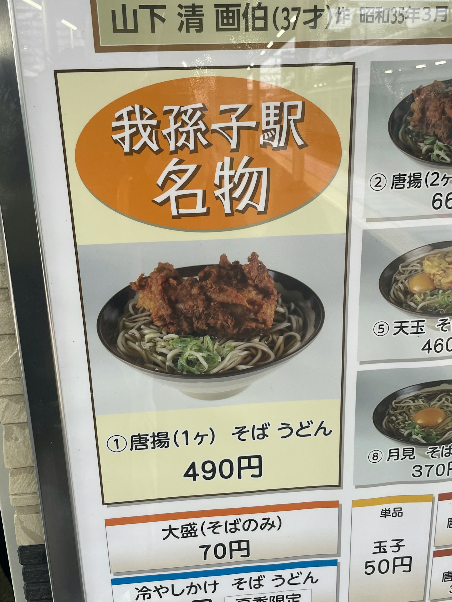Bild eines Menüschildes mit berühmten Gerichten von Yamashita Kiyoshi, darunter gebratenes Hähnchen und Soba Udon