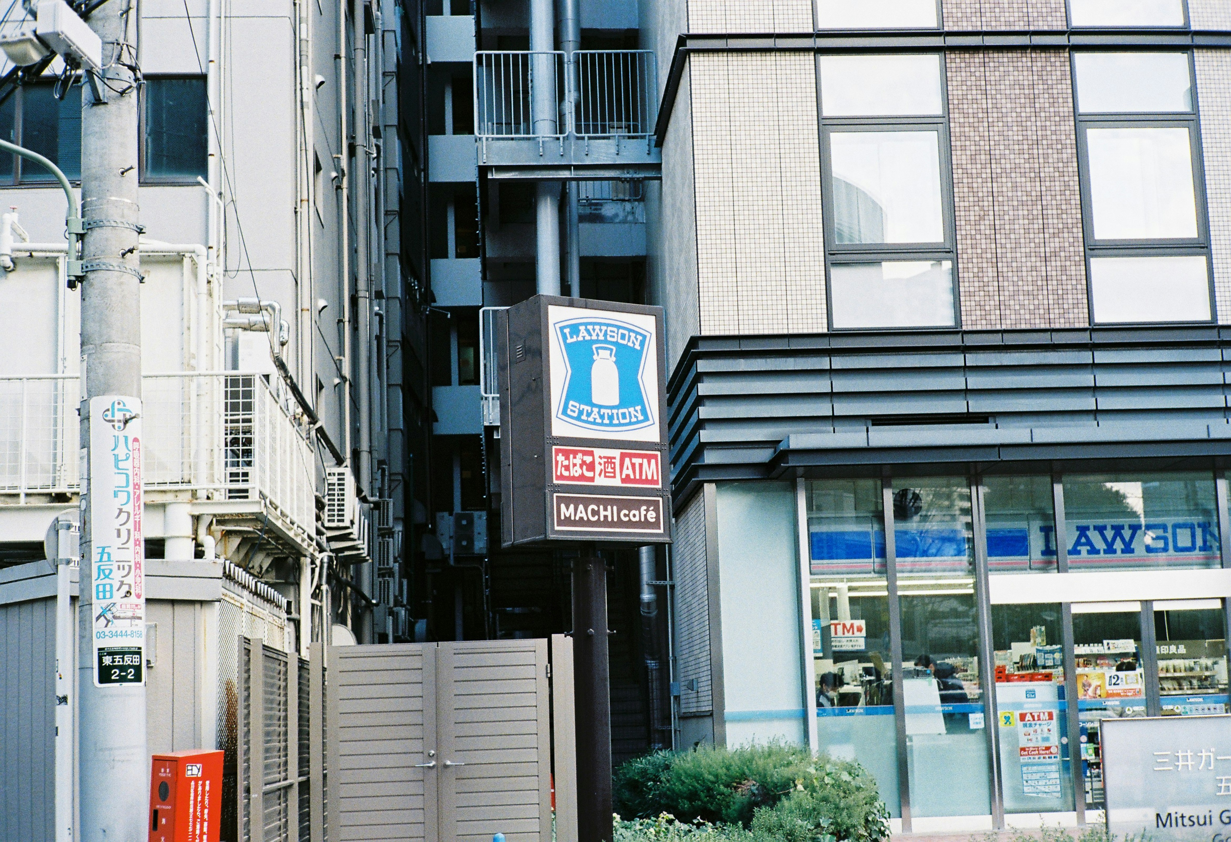 路地に面したATMと看板のあるビル外観