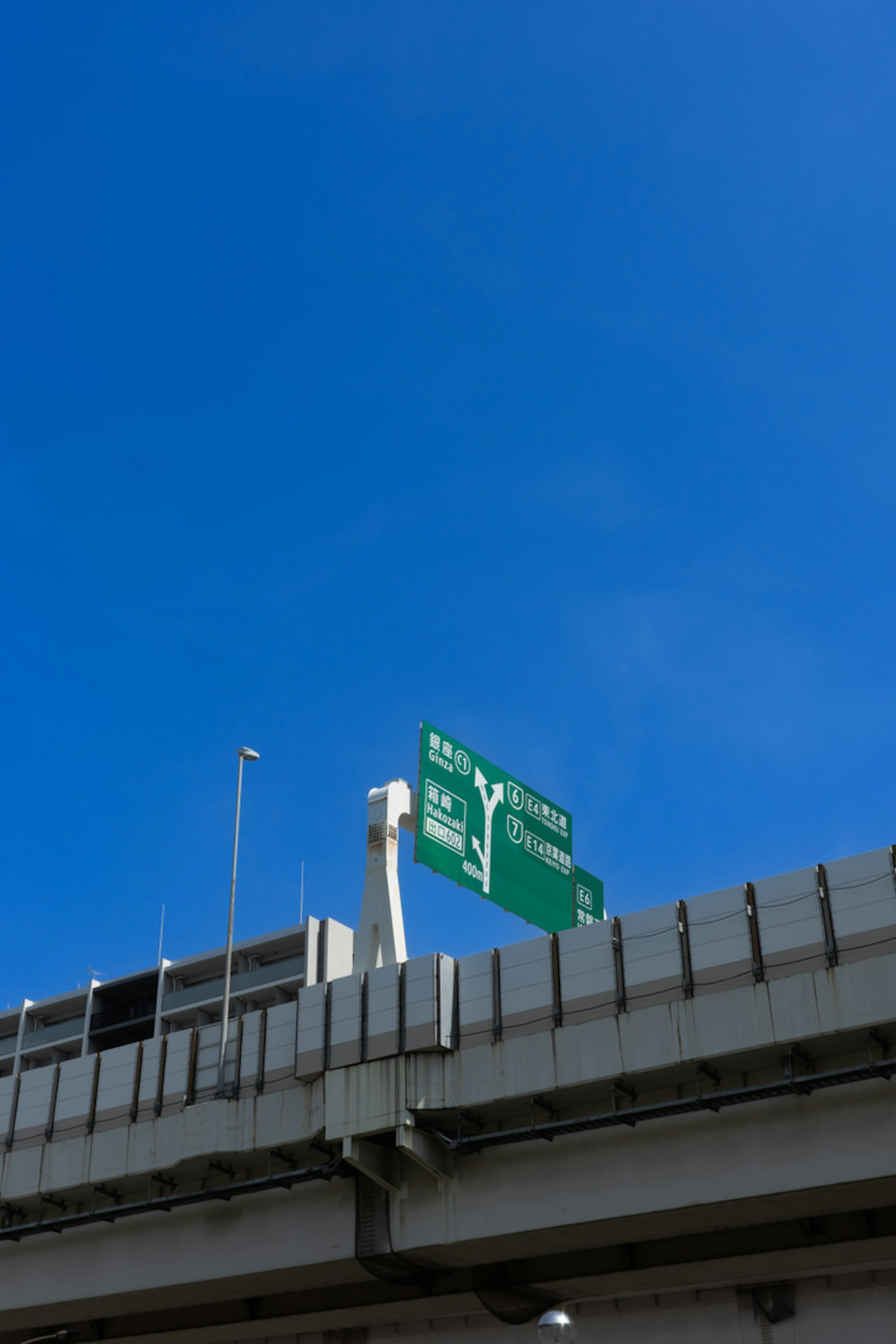Panneau de route et partie d'un pont sous un ciel bleu clair