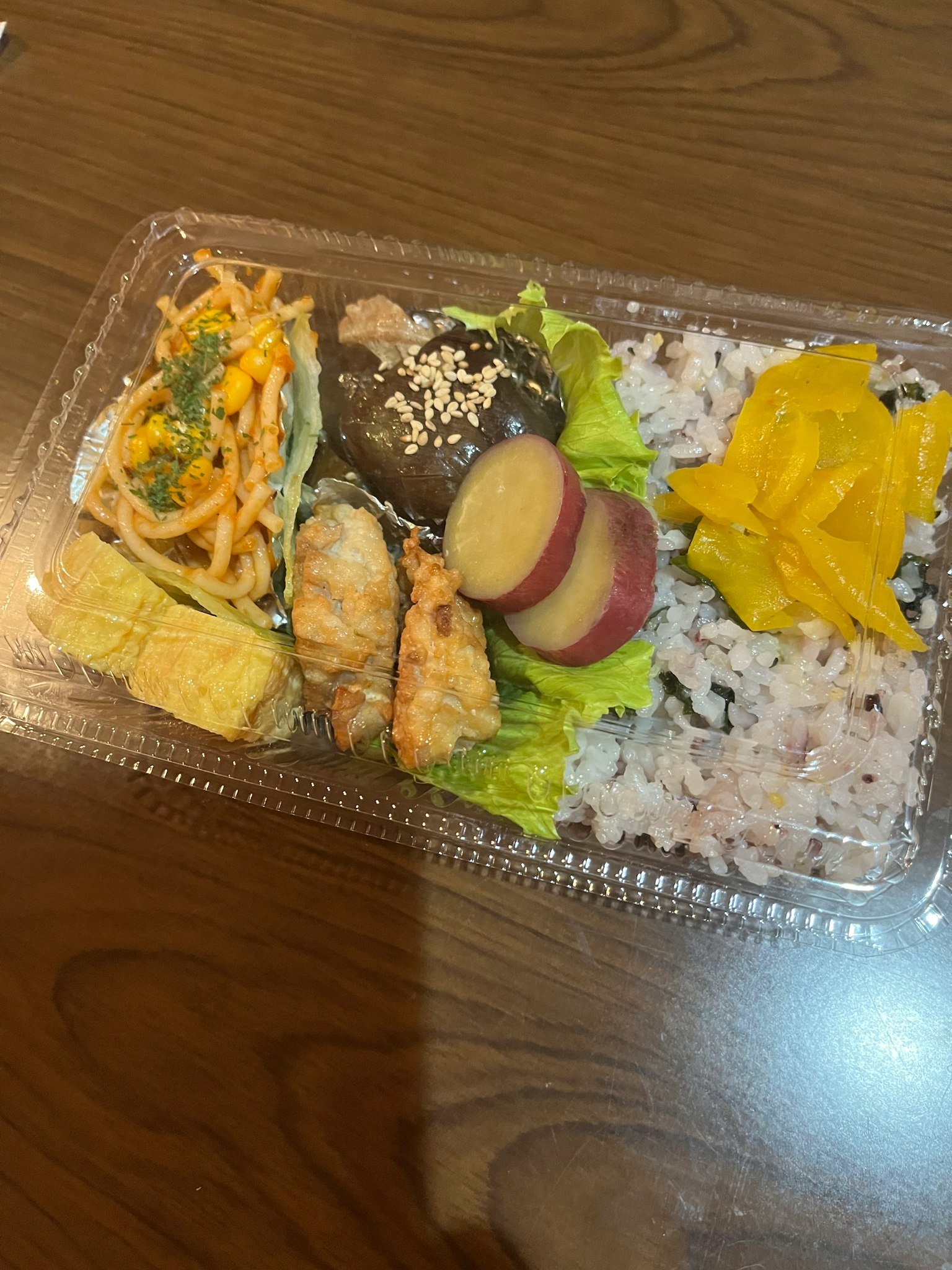 Variedad de bento japonés que incluye pollo frito, verduras guisadas, tamagoyaki, ensalada, arroz y verduras encurtidas