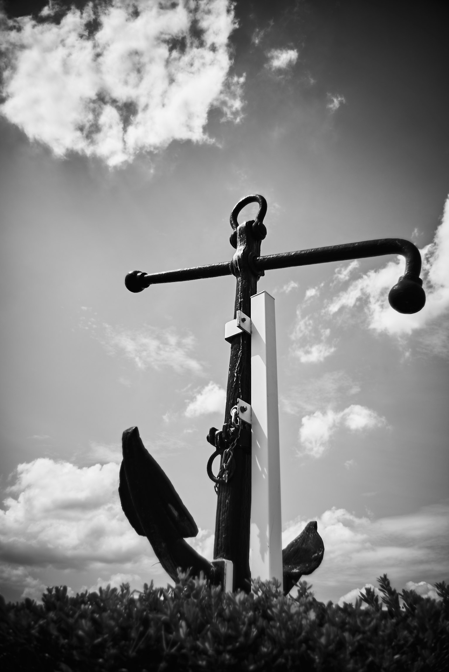 Large ship anchor against a black and white background with blue sky