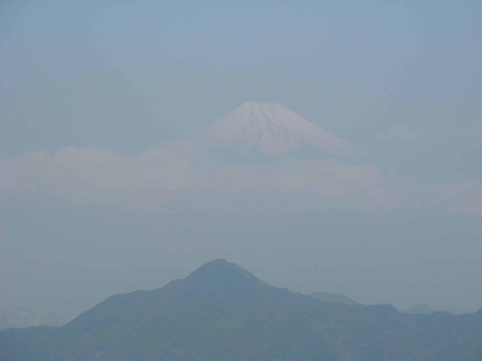 Monte Fuji parzialmente oscurato da leggeri nuvoloni sotto un cielo blu