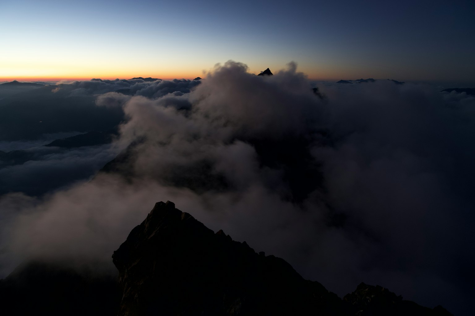 Vue des nuages et du coucher de soleil depuis un sommet de montagne