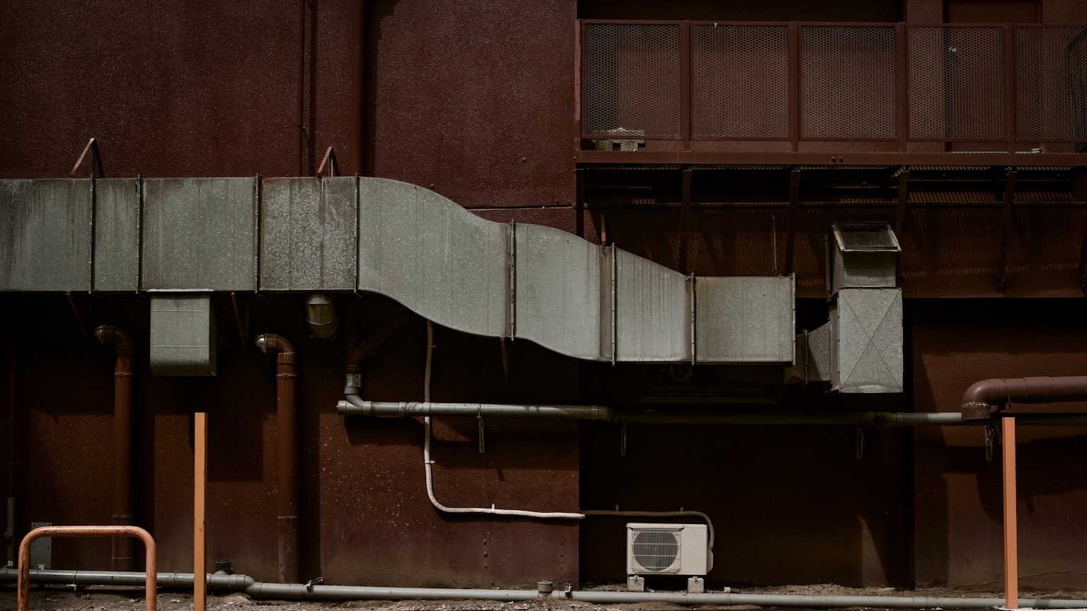 Vista dettagliata di condotti metallici e tubazioni attaccati a un muro marrone rossastro