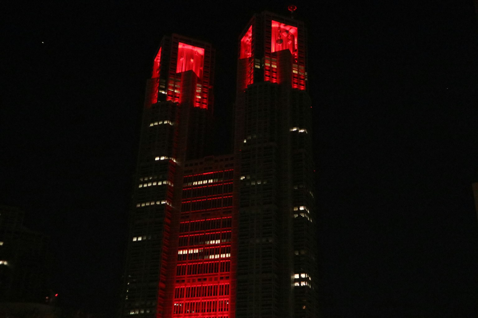 Menara kembar Gedung Pemerintah Metropolitan Tokyo yang diterangi merah di malam hari