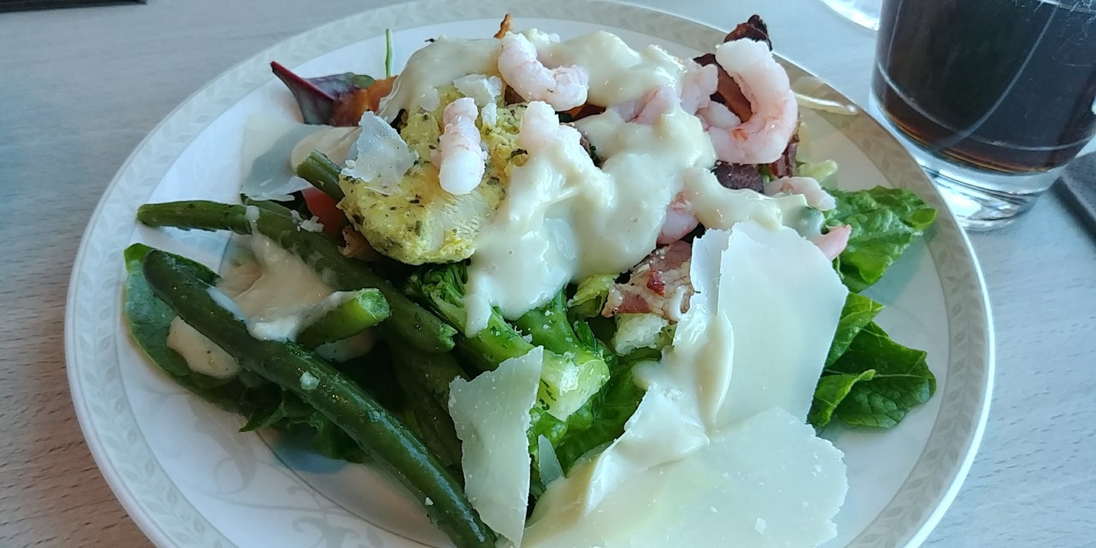 Plate of salad topped with shrimp and creamy dressing
