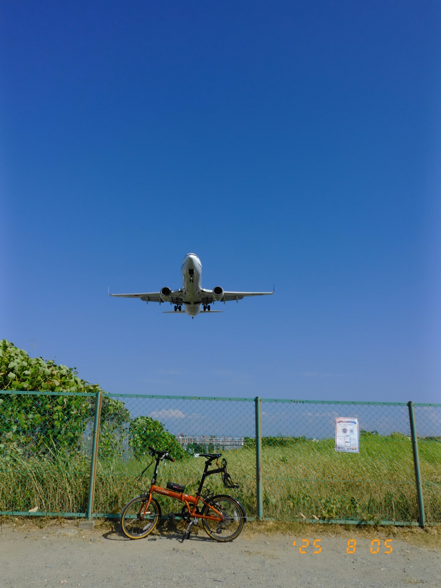Un avión aterrizando bajo un cielo azul con una bicicleta en primer plano