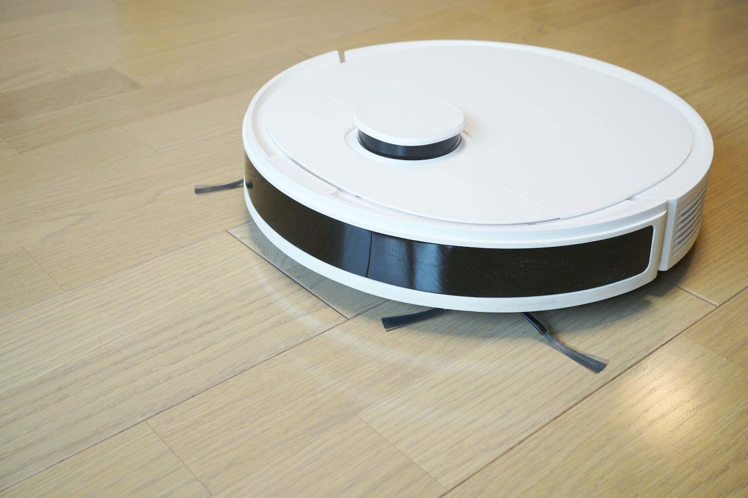 Un aspirateur robot blanc se déplaçant sur un sol en bois