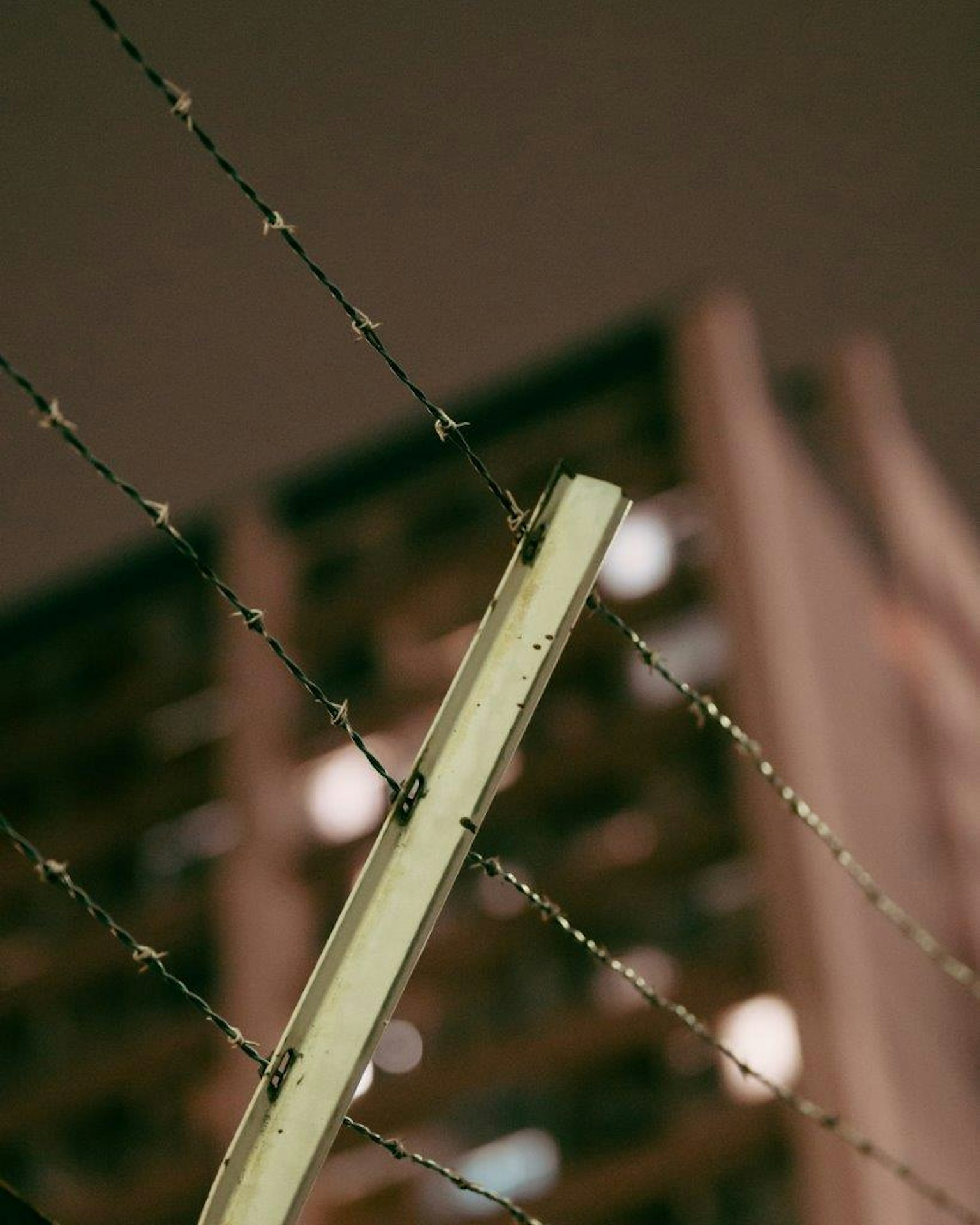 Valla de alambre de púas con un edificio borroso en el fondo nocturno