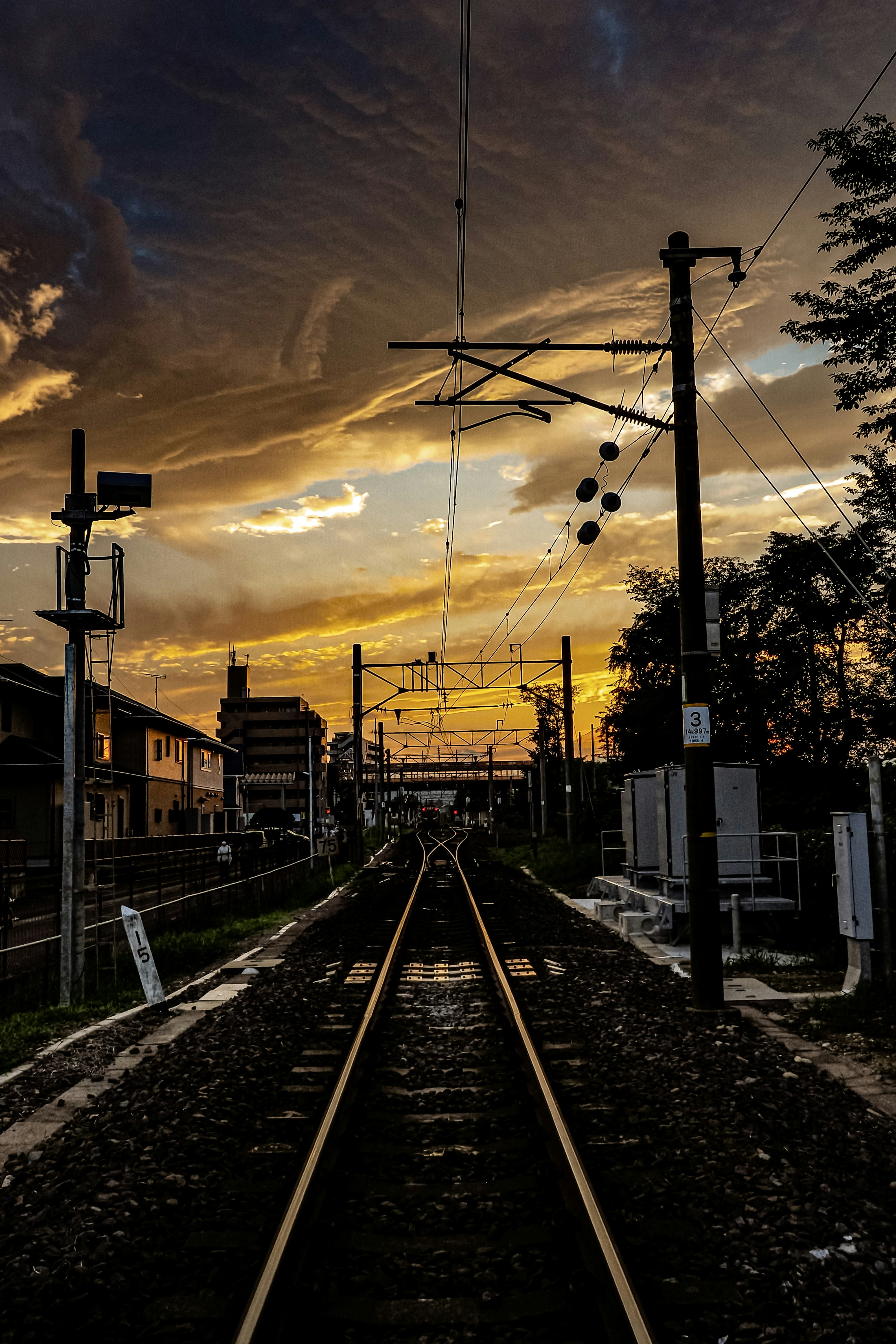 tramonto sui binari ferroviari con pali elettrici in un contesto rurale